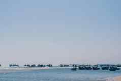 苍白的粉红色的紫色的灰色的语气海景清晰的天空视图真正的自然美背景电动机船帆停靠浅水边缘沙子海滩湾平静涟漪海钓鱼生活风格旅行休闲旅行