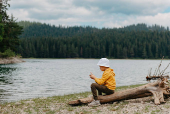男孩坐着日志山湖孤独的男孩坐在安静地之前美丽的视图山男孩湖男孩湖度假胜地