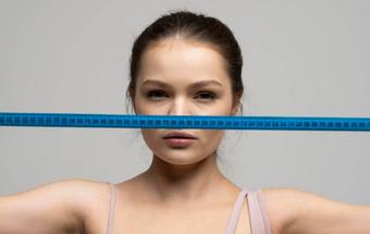 关闭肖像有吸引力的浅黑肤色的女人女人绿色眼睛持有蓝色的测量磁带前面脸相机重量损失饮食概念