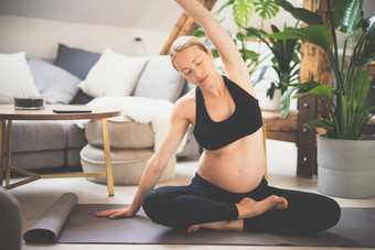 年轻的美丽的怀孕了女人培训瑜伽首页生活房间母亲怀孕健康的生活方式瑜伽概念