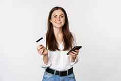 微笑现代女人信贷卡移动电话支付使购买在线购物智能手机站白色背景