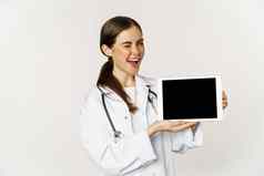 图像女人医生女医疗保健工人显示在线医疗网站数字平板电脑屏幕微笑站白色外套白色背景