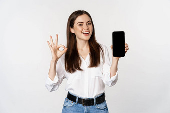 快乐微笑女人满意脸推荐优秀的应用程序显示移动电话屏幕标志站白色背景