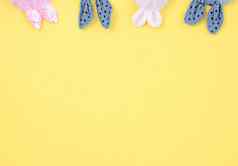 粉红色的蓝色的织物兔子耳朵黄色的背景复活节概念