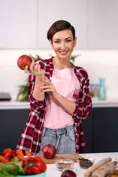 苹果手快乐女人选择水果烹饪厨房相机家庭主妇烹饪苹果馅饼站厨房穿格子衬衫短头发