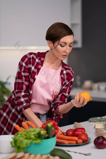 年轻的漂亮的家庭主妇鲍勃发型准备食物厨房选择番茄红色的黄色的健康的食物首页健康的食物离开素食主义者概念