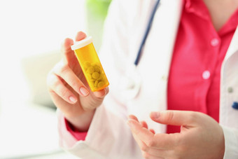 医生持有塑料容器填满小白色药片女实习生广告药物治疗