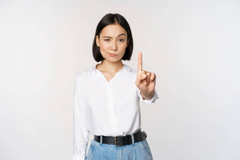 年轻的自信亚洲女人显示停止手指手势禁忌标志站白色背景