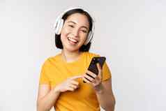 可爱的日本女孩耳机移动电话微笑音乐应用程序智能手机站白色背景
