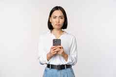 亚洲女人持有智能手机怀疑失望移动电话应用程序站阿加斯特白色背景
