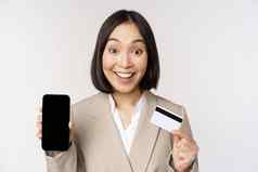企业女人快乐热情的脸显示信贷卡智能手机应用程序屏幕站西装白色背景