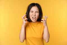 图像愤怒的亚洲女人大喊大叫诅咒愤怒的愤怒的脸表达式站黄色的背景