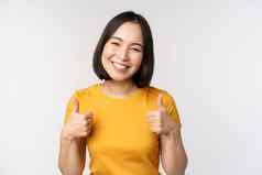 美丽的微笑亚洲女模型显示拇指很高兴推荐表达积极的反馈站白色背景