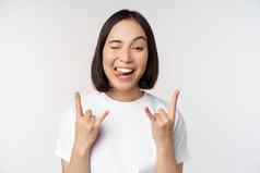 时髦的亚洲女孩大喊大叫享受音乐会节日显示岩石重金属标志有趣的站白色背景