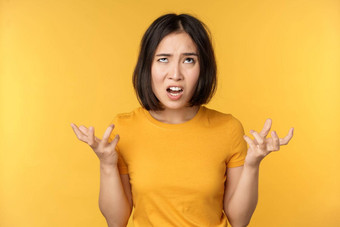 图像愤怒的亚洲女人大喊大叫诅咒愤怒的愤怒的脸表达式站黄色的背景