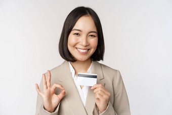 微笑办公室职员亚洲企业女人显示信贷卡标志<strong>推荐</strong>银行站白色背景米色西装