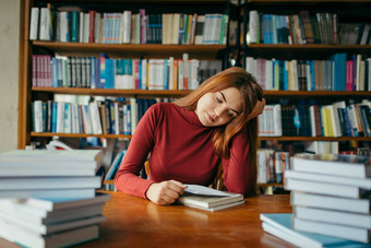 女孩持有书架子上学生图书馆