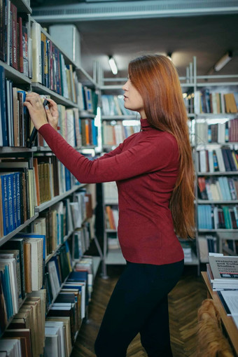 女孩持有书架子上学生图书馆