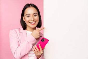 图像微笑亚洲企业女人西装持有智能手机指出董事会显示图表信息标志空白色墙站粉红色的背景