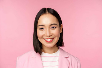 关闭肖像亚洲企业女人专业微笑相机穿西装站粉红色的背景