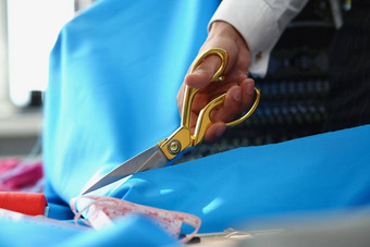人切割蓝色的棉花布剪刀工具缝纫