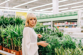 园艺种植购物概念美丽的成熟的成人女人选择室内植物锅温室花园中心高级购买花植物市场商店购物中心