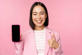 满意微笑亚洲女商人推荐移动电话应用程序网站公司智能手机显示屏幕拇指粉红色的背景