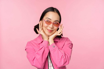 肖像时尚的可爱的亚洲女孩微笑触碰脸梦幻深思熟虑的站粉红色的背景