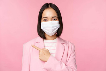 肖像亚洲女商人医疗脸面具西装指出手指左显示广告公司横幅工作室粉红色的背景