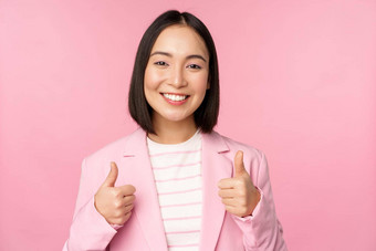 专业女商人亚洲企业女人显示拇指微笑赞美赞美站西装粉红色的背景