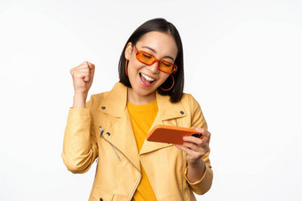 时尚的朝鲜文女孩太阳镜玩移动视频游戏笑微笑智能<strong>手机</strong>站白色背景