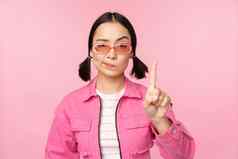 图像时尚的亚洲女孩太阳镜显示停止禁止手势禁忌标志站粉红色的背景