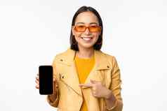 肖像时尚的朝鲜文女孩太阳镜微笑指出手指智能手机屏幕显示移动电话应用程序站白色背景