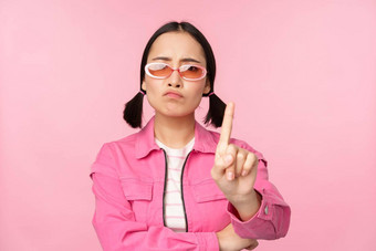 图像时尚的亚洲女孩太阳镜显示停止禁止手势<strong>禁忌</strong>标志站粉红色的背景