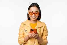 现代亚洲女孩太阳镜移动电话微笑快乐摆姿势白色背景