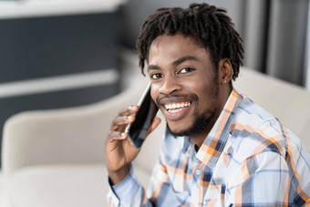 年轻的非洲美国的家伙电话手相机<strong>谈话</strong>肖像快乐男人。现在<strong>谈话</strong>坐着沙发社会媒体概念