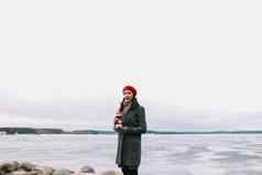冬天肖像年轻的女人外套红色的他持有装饰灯塔站海岸冻海冬天旅行海背景多风的天气冰海边