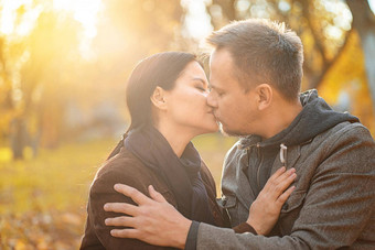 夫妇爱接吻太阳闪亮的丈夫妻子接吻阳光明媚的草地秋天森林特写镜头秋天背景