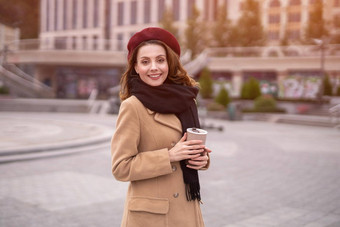 巴黎年轻的女人持有可重用的杯子咖啡站在户外肖像时尚的年轻的女人穿秋天外套红色的贝雷帽在户外秋天配件