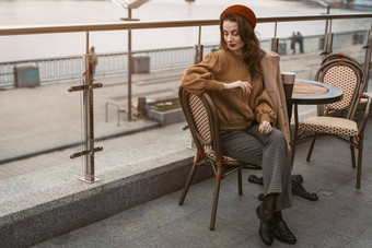 等待沮丧法国年轻的女人坐着在户外街餐厅沮丧肖像时尚的年轻的女人穿秋天外套红色的贝雷帽在户外