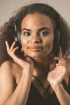 年轻的非裔美国人女孩听音乐耳机穿黑色的前孤立的灰色背景在情感上移动概念情绪面部表达式销售包容