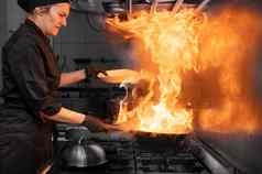 女人老板烹饪锅厨房烹饪燃烧的锅蔬菜商业厨房