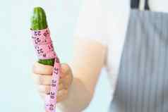 人持有黄瓜测量磁带饮食健康的有机食物
