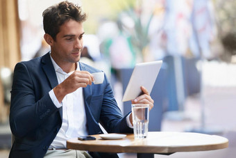 捕捉在线快报拍摄年轻的商人坐着户外咖啡馆数字平板电脑