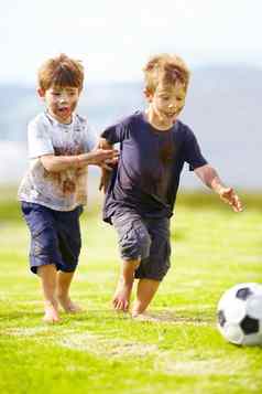 友好的游戏可爱的男孩玩足球覆盖泥
