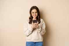 人细胞技术美丽的时尚的女人移动电话智能手机应用程序微笑屏幕站米色背景