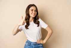 肖像现代年轻的女人显示拇指批准微笑很高兴推荐公司网站站米色背景