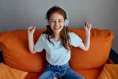 快乐的女人橙色沙发听音乐耳机生活方式