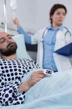 脉冲血氧计病人手指显示低氧气饱和中间岁的男人。医生调整滴行