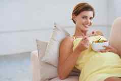 采取婴儿健康关注饮食肖像年轻的怀孕了女人享受健康的沙拉放松沙发上
